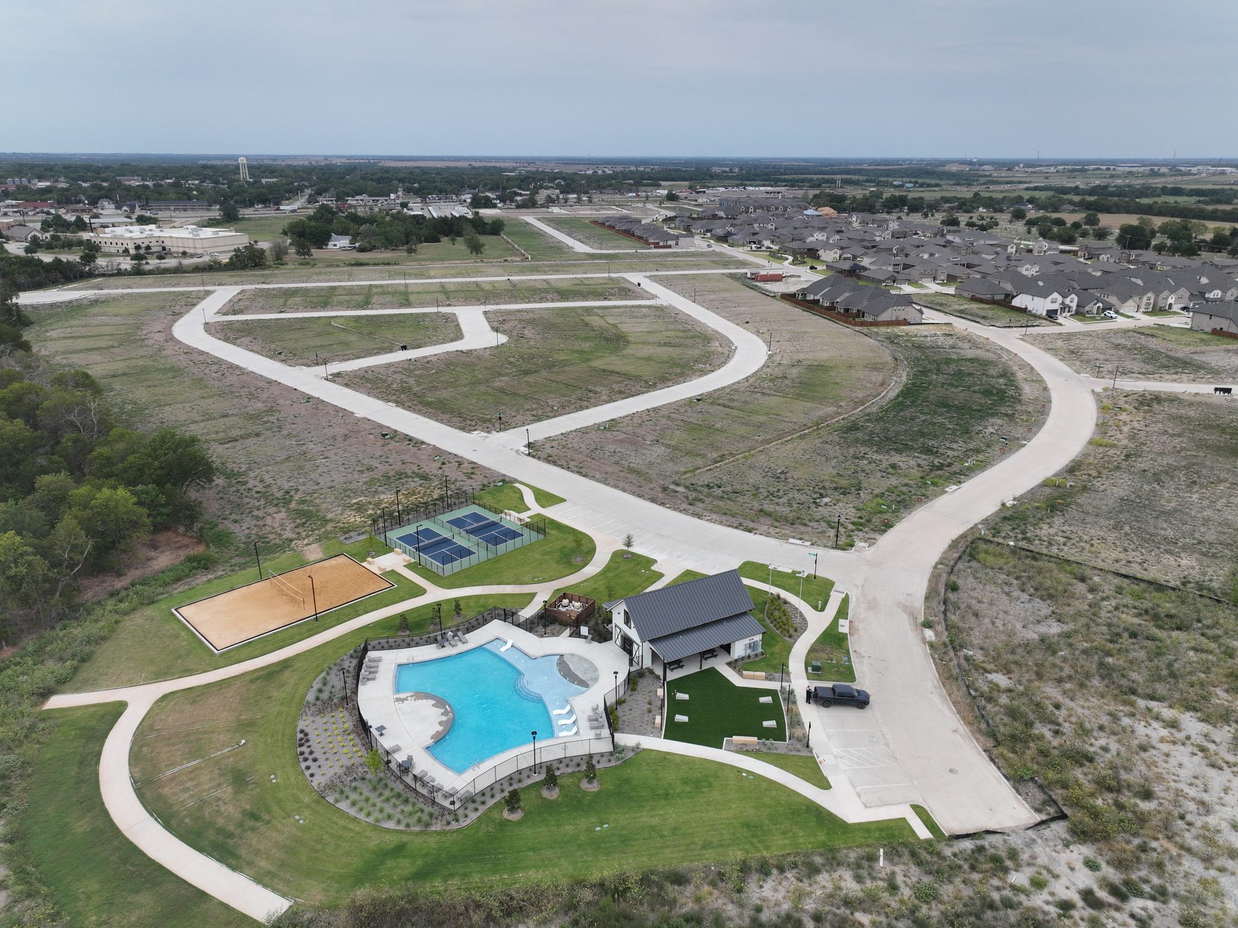 Aerial view of the completed amenity center and finished homes set among the street network at Liberty Crossing Phase 1 in Royse City, Texas