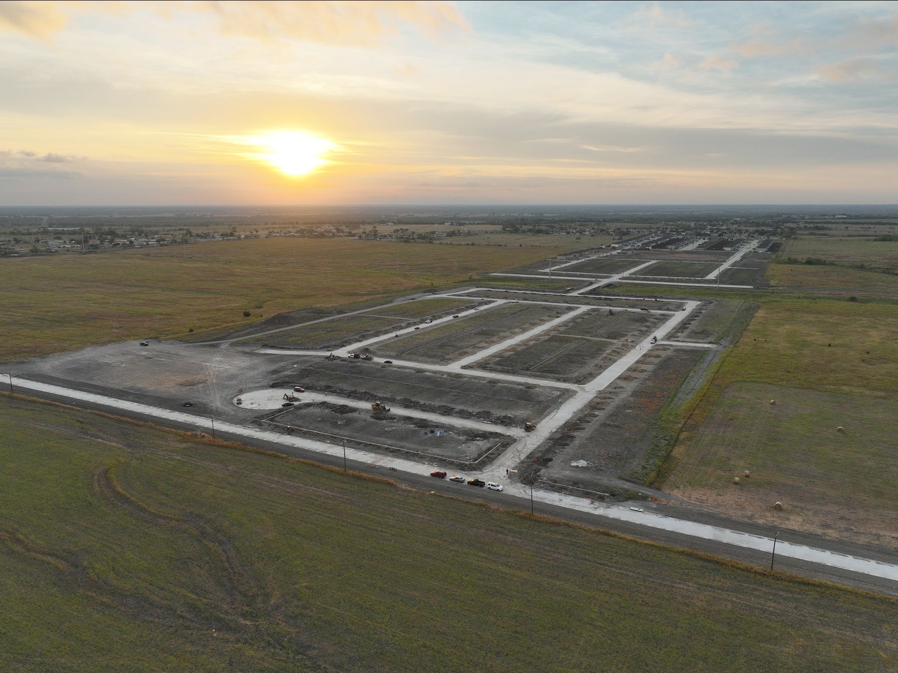 Aerial view at sunrise of newly paved streets and graded homesites under development at Cartwright Mays in Crandall, Texas