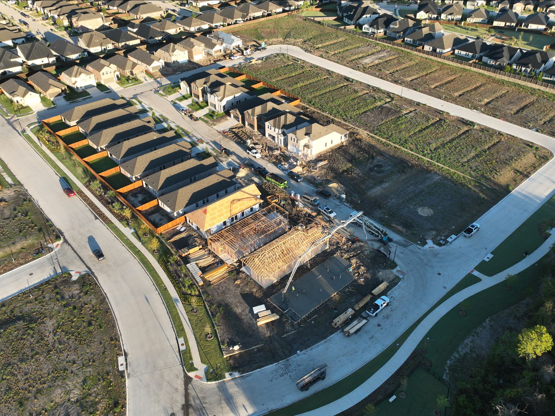 Aerial view of homes being framed beside a row of finished homes and delivered homesites at Elevon Section 1, Phase 4 in Lavon, Texas